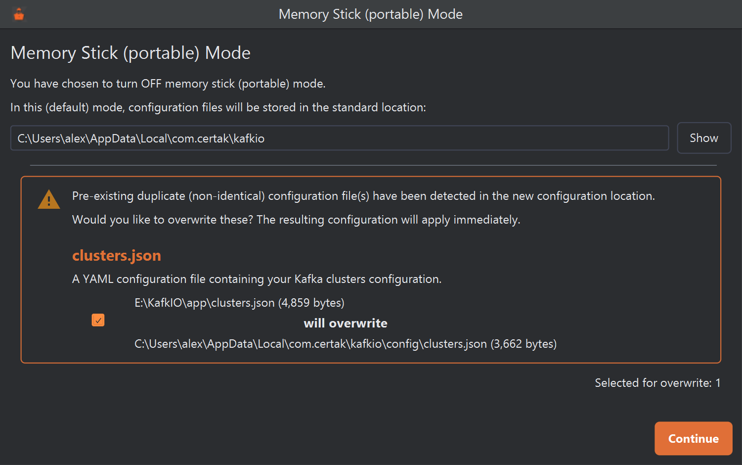 The Memory Stick (portable) Mode window after choosing to turn the mode off. The standard location is C:\Users\alex\AppData\Local\com.certak\kafkio. A warning box says pre-existing duplicate (non-identical) configuration files have been detected in the new configuration location and asks whether to overwrite them. It lists clusters.json, with a ticked checkbox: E:\KafkIO\app\clusters.json (4,859 bytes) will overwrite C:\Users\alex\AppData\Local\com.certak\kafkio\config\clusters.json (3,662 bytes). Below it reads Selected for overwrite: 1, and a Continue button.